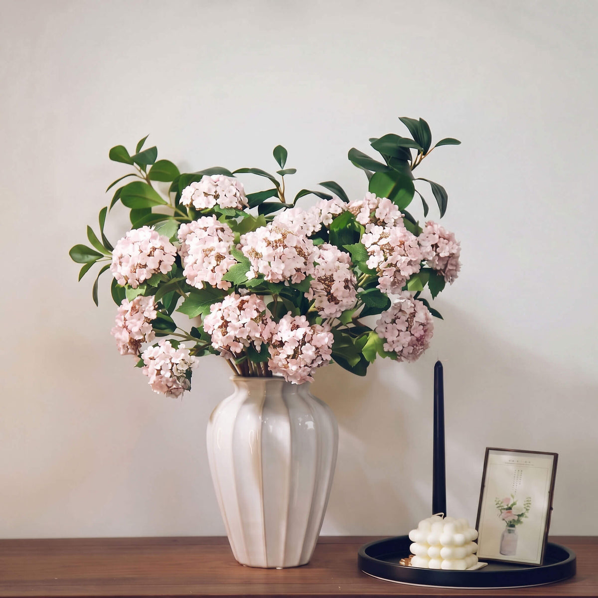 Artificial hydrangea arrangement featuring soft pink blooms arranged in a white ceramic vase, creating an elegant floral centerpiece for home decor.