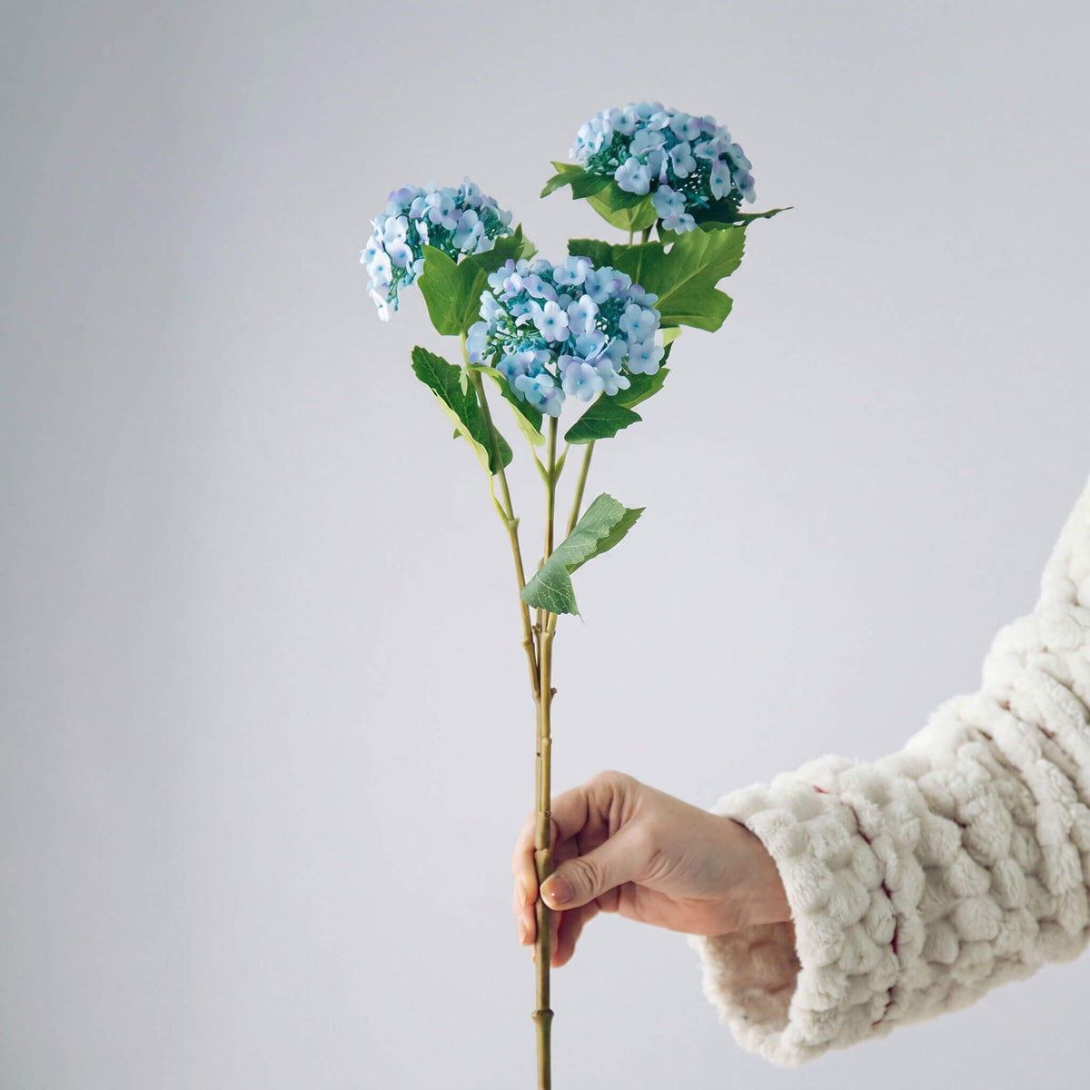 Single blue artificial hydrangea bloom showcasing lifelike color gradients and delicate petal structure.