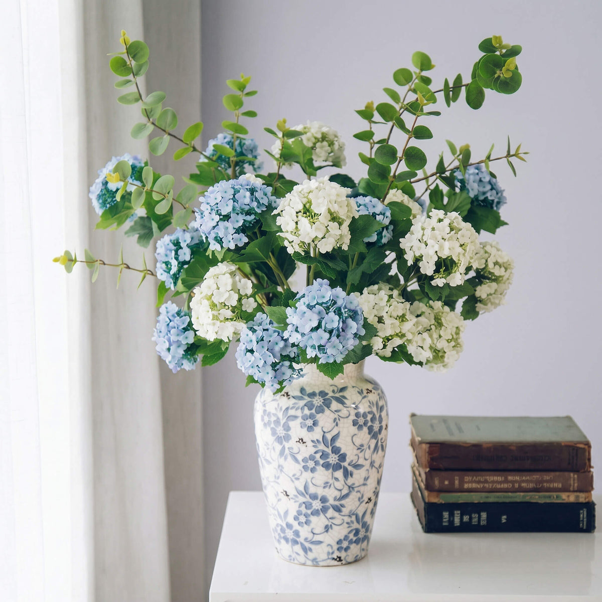 Artificial hydrangea arrangement in a blue and white porcelain vase, elegant faux floral centerpiece for home decor.