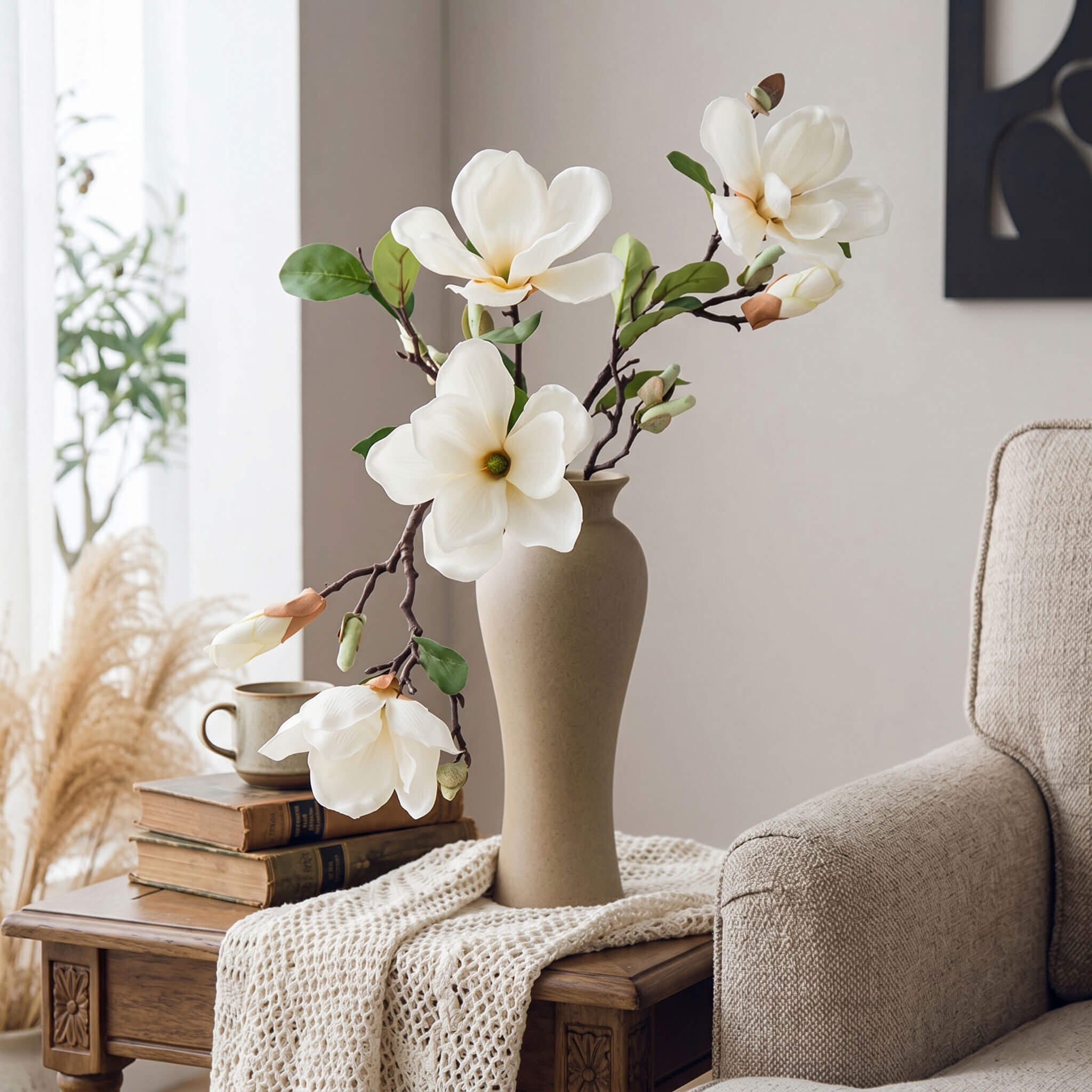 Faux magnolia arrangement styled in a living room, displayed on a side table with a curved pale yellow vase.