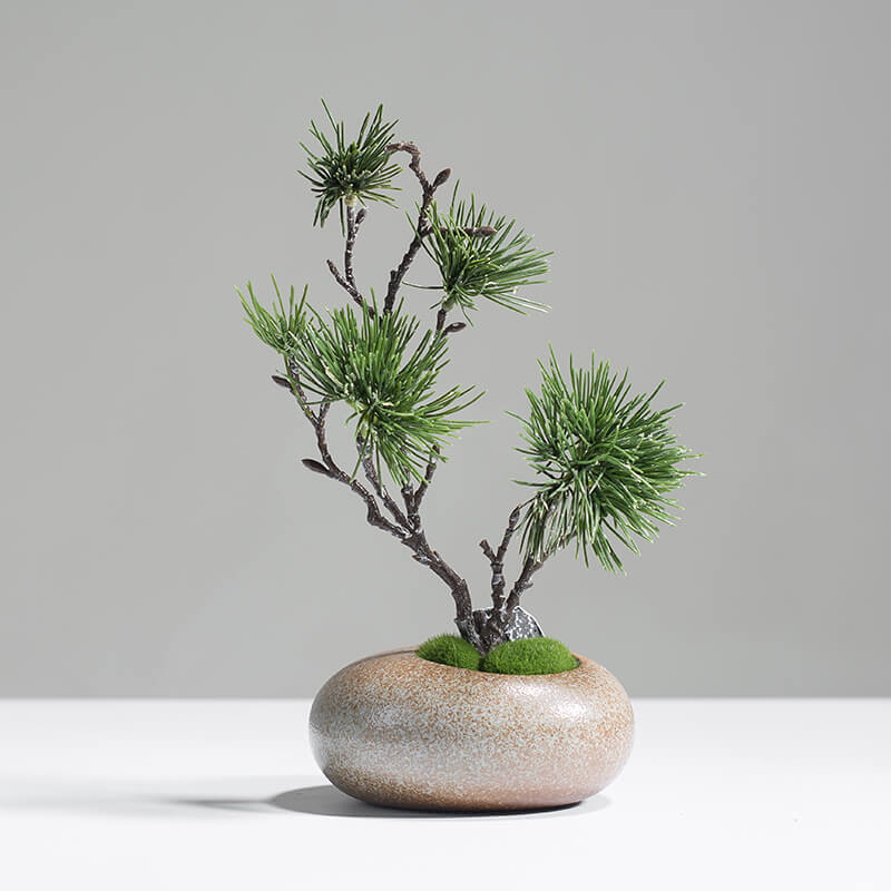 Minimalist artificial pine tree in brown ceramic vase styled on a side table for modern home decor