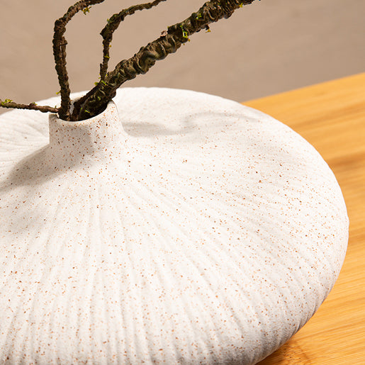 White ceramic vase detail of artificial ficus plant arrangement