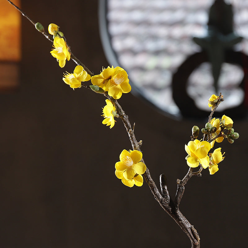 Yellow artificial plum blossom shown from the front, highlighting bright tones and delicate floral structure.