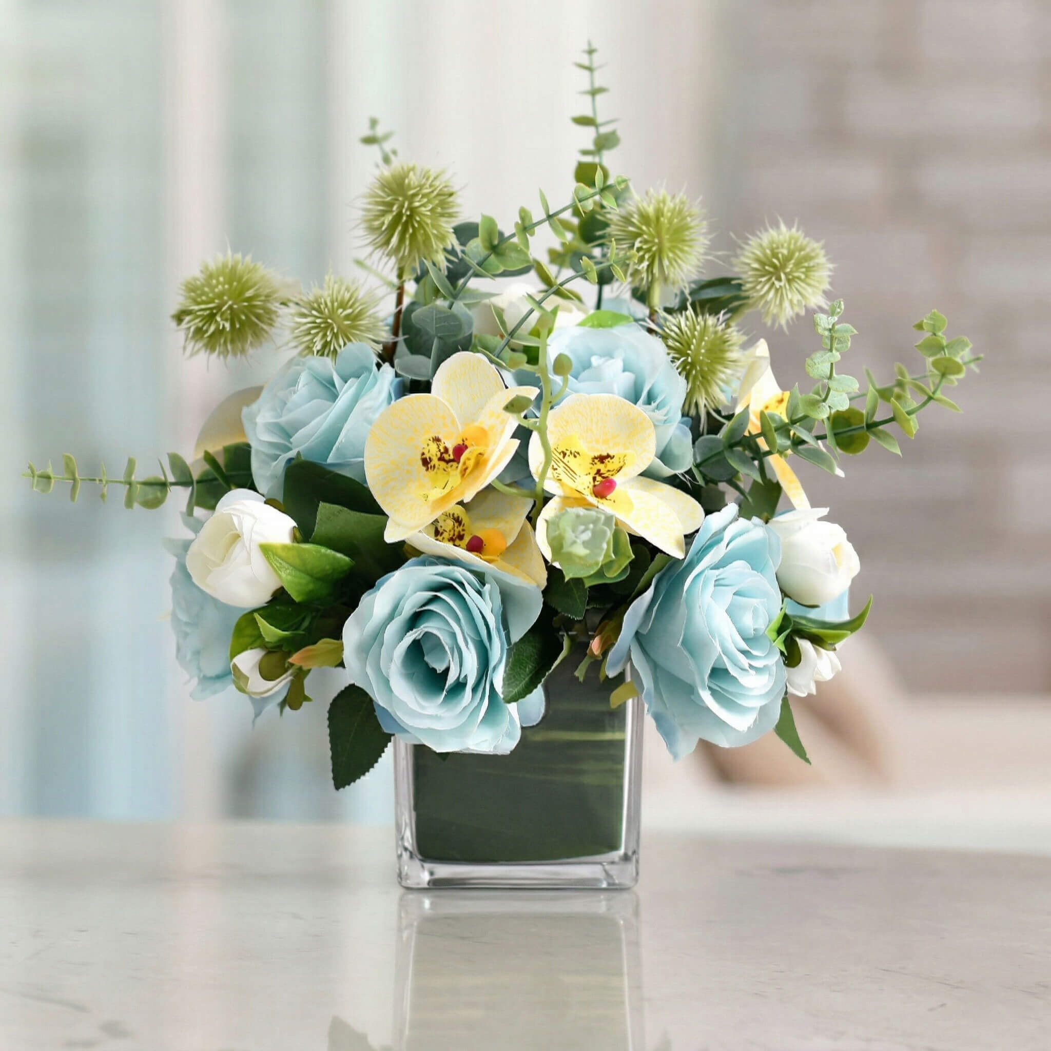 Blue artificial orchid and rose floral arrangement with eucalyptus