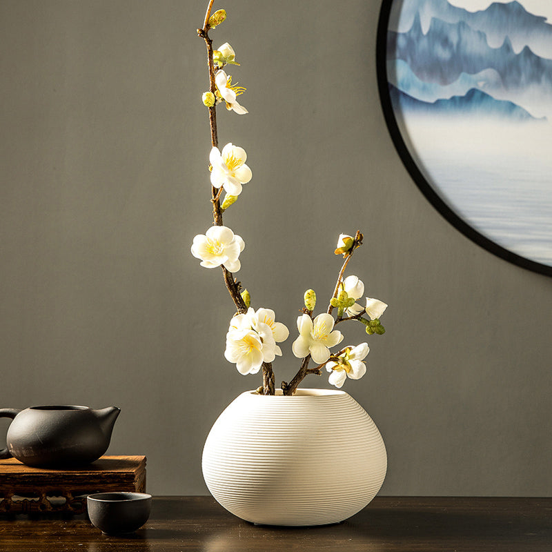 White artificial plum blossom arrangement in a ceramic vase, offering a clean and minimalist decorative accent.