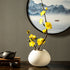 Yellow artificial plum blossom arrangement styled in a white ceramic vase, adding a bright and cheerful touch to interiors.