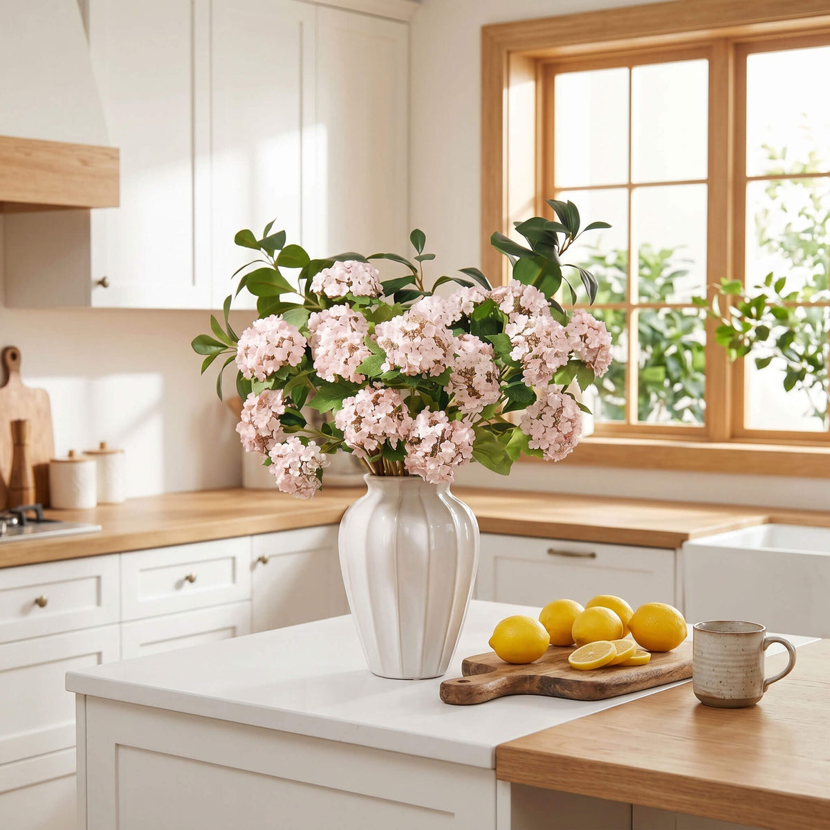 Faux hydrangea arrangement in a white ceramic vase styled on a farmhouse kitchen island for a timeless cottage-inspired look.