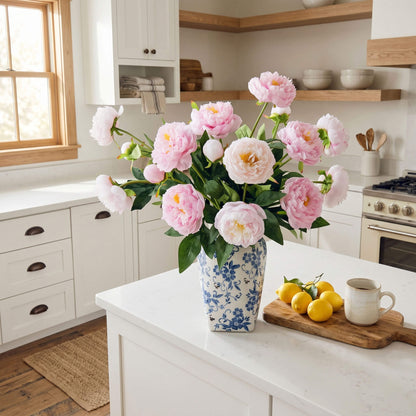 Blue and white porcelain vase filled with faux peonies displayed on a farmhouse kitchen island as a charming floral centerpiece.