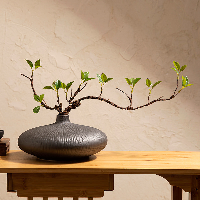 Minimalist artificial ficus plant in black glazed ceramic vase styled on a side table for zen-inspired home decor