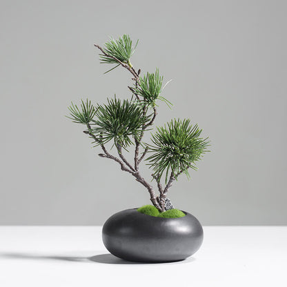 Minimalist artificial pine tree in black ceramic vase styled on a side table for modern home decor