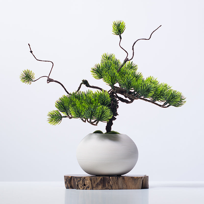 Minimalist artificial pine tree in white ceramic vase styled on a side table for modern home decor